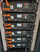 Six stacked Rich Solar Alpha 5 Pro lithium iron phosphate batteries featuring active LCD status screens and parallel cabling.