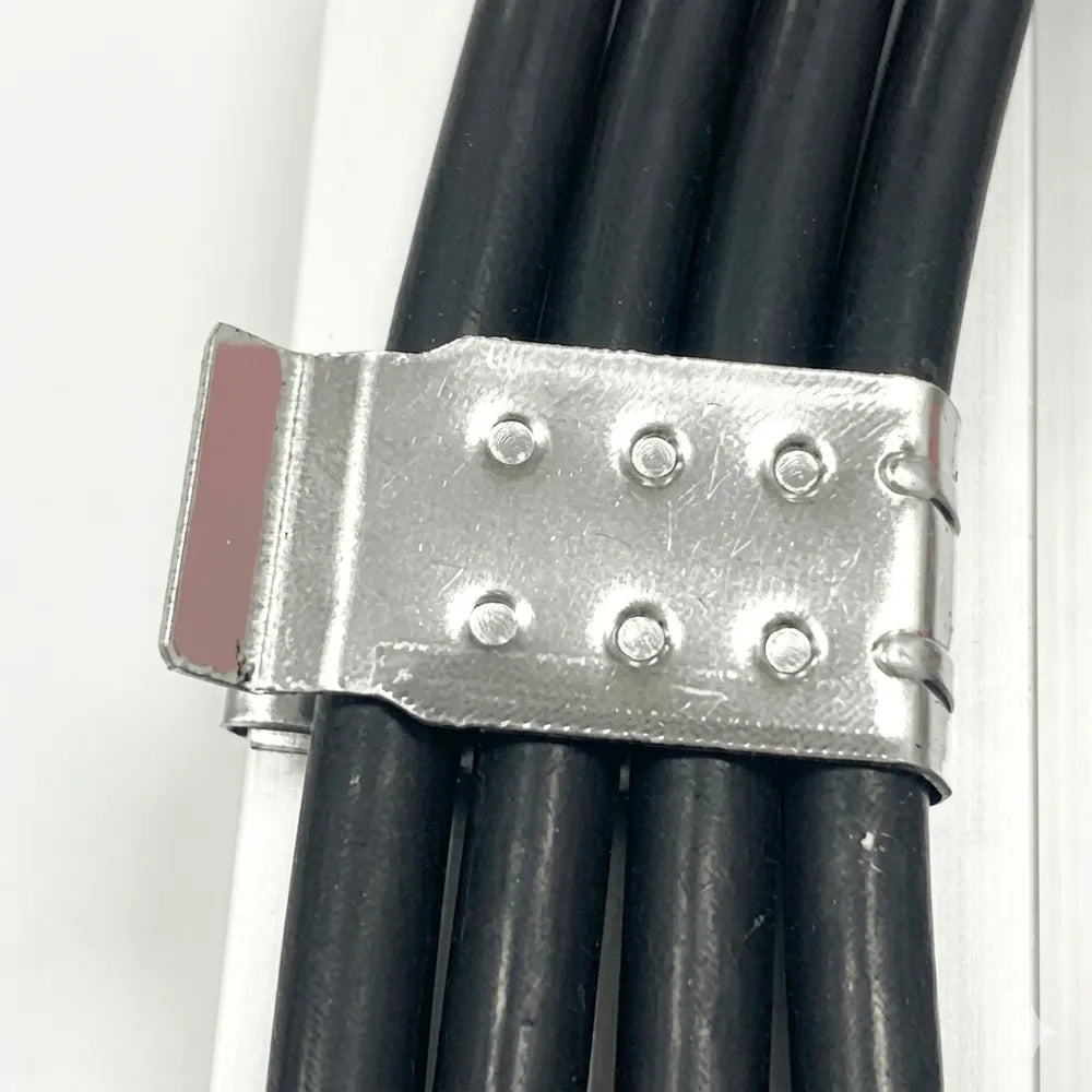 Close-up of a silver metal solar cable clip gripping several black PV wires along a panel frame, designed for cable routing and strain relief.