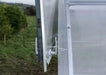 Close-up detail of the secure white handles and hardware on the Dutch door of a Daisy greenhouse kit.